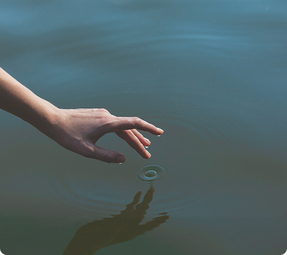 Hand touching water to create a ripple