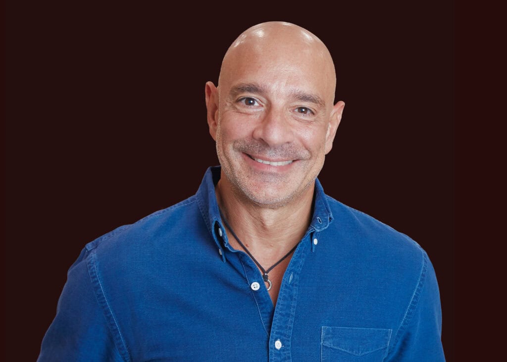 Bald man smiling in blue shirt, promoting smart health decisions and healthcare innovation.